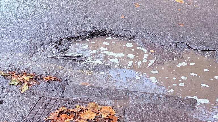 A pothole with a big puddle in it